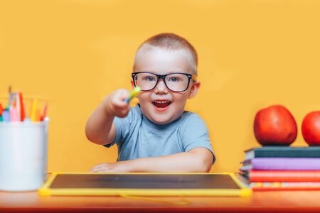 Little boy painting and doing homeworks on his desk having an idea, inspiration concept. back to school on yellow background.の写真素材