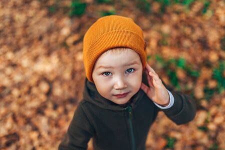 Kid Autumn Fashion Season, Child in Hat Jacket Clothing, Boy with Fall Leaves Looking at camera, three years old.の写真素材