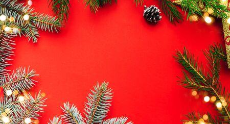 Frame of christmas decoration of spruce, cone, star on red background, blue and green spruce, flat lay, space for text.の写真素材