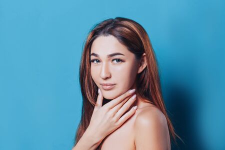 Beautiful brunette girl with clean skin and big eyes on blue background.の写真素材