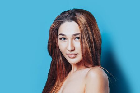 Beautiful brunette girl with clean skin and big eyes on blue background.の写真素材