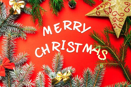 Wooden letters of Merry Christmas words on red background flat lay top view, frame of branches of spruce, lights.の写真素材
