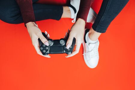 Young woman playing with gamepad on red.の写真素材