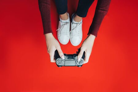 Young woman playing with gamepad on red.の写真素材