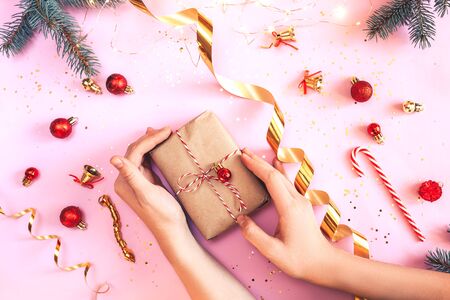 Woman holding christmas gifts. Flat lay foto with christmas decorations on pink background.の写真素材