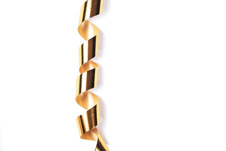 Christmas gold serpentine curling ribbon hanging on white background. Isolated.の写真素材