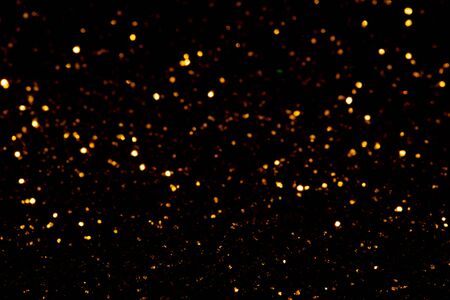Golden glitter bokeh lights on black background, unfocused. Holiday time.の写真素材