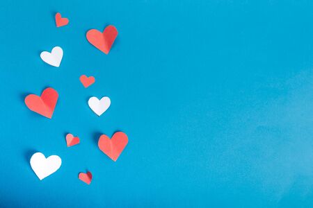 Valentine's Day background. White and red hearts on blue background and one present card with red heart. Valentines day concept. Flat lay, top view, copy space.の写真素材
