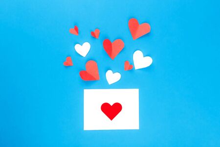 Valentine's Day background. White and red hearts on blue background and one present card with red heart. Valentines day concept. Flat lay, top view, copy space.の写真素材
