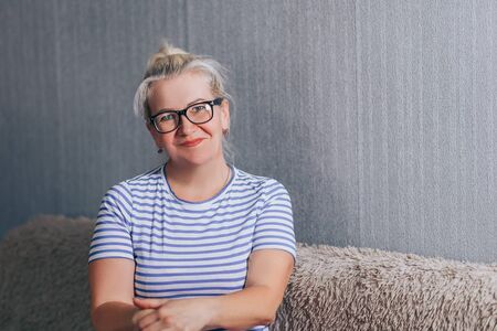 Smiling mature woman sitting on sofaの写真素材
