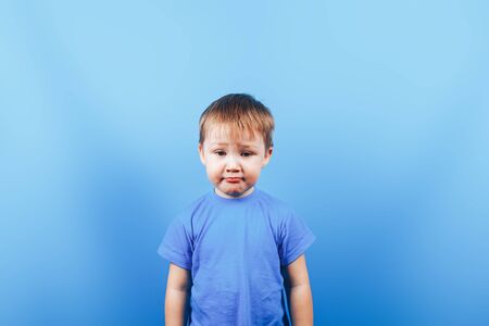 Upset crying sad boy at blue backgroundの写真素材