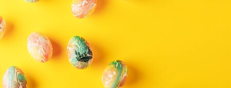 Easter eggs painted in orange and green colors on yellow background