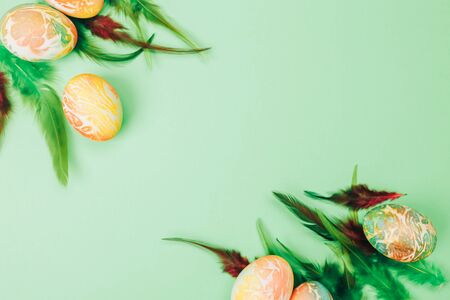 Easter eggs painted in orange and green colors on yellow backgroundの写真素材
