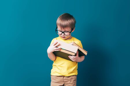Happy schoolboy in glasses holding booksの写真素材
