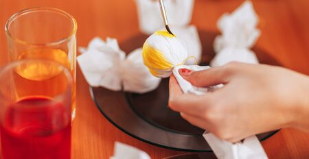 Preparing to Easter, Woman paint and color eggs with the help of napkins.の写真素材
