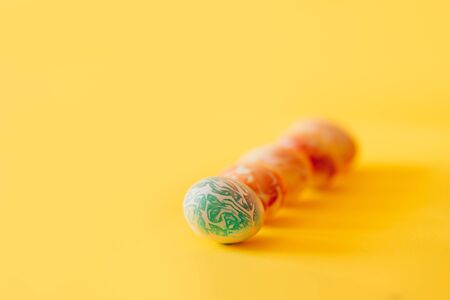 Color easter eggs differen patterns. Line of eggs on yellow backgroundの写真素材
