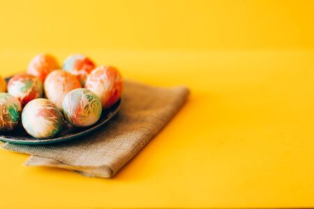 Easter eggs with ornament on green plate with napkinの写真素材