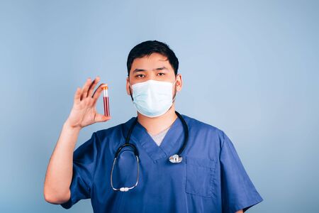 The doctor holds in his hands a test tube with bloodの写真素材