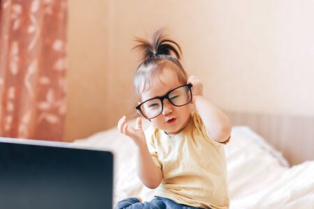 Little happy funny black-haired girl using laptopの写真素材