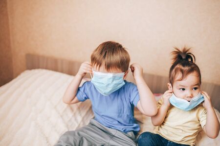 Two children brother and sister in medical masks using laptopの写真素材
