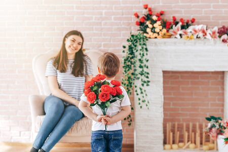 Boy holding a bouquet of flowers behind his backの写真素材