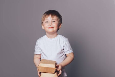 Beautiful little boy holding boxes in handsの写真素材