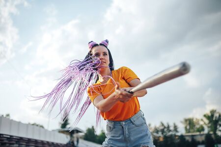Young beautiful girl holding a baseball bat in a yellow open-air t-shirt in a sports stadium.の写真素材