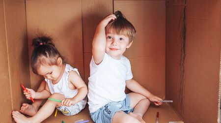 Beautiful little children draw with felt-tip pens and play in box, activity for children at home.の写真素材