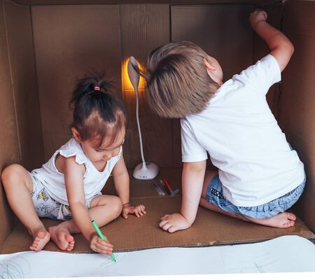 Beautiful little children draw with felt-tip pens and play in box, activity for children at home.の写真素材