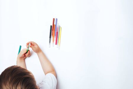 Little child draws on white paper with colored felt-tip pens, teaching children to draw.の写真素材