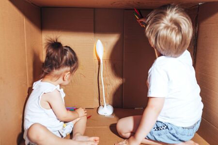 Beautiful little children draw with felt-tip pens and play in box, activity for children at home.の写真素材