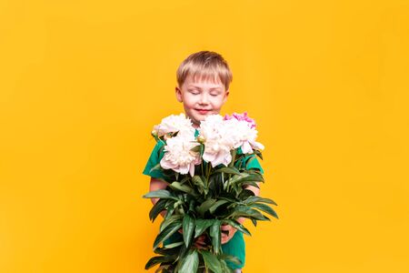Little boy holding a bouquet of beautiful flowers in his hands, mothers day, March 8, fathers dayの写真素材