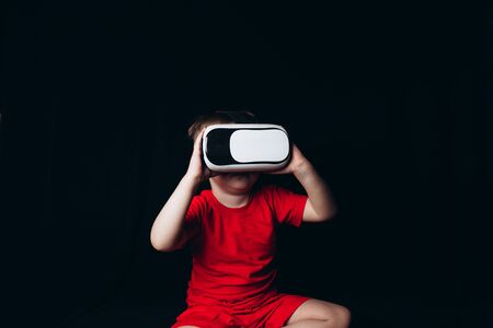 Small Boy experiencing virtual reality on black background with light luminous effectsの写真素材
