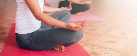 Beautiful young girl doing yoga on the mat, relaxes, taking care of health.の写真素材
