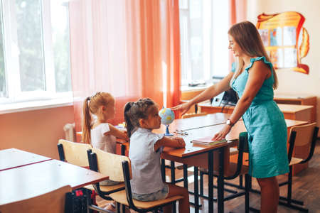 Geography teacher shows two schoolgirls on a globe, individual tuition, elective.の写真素材