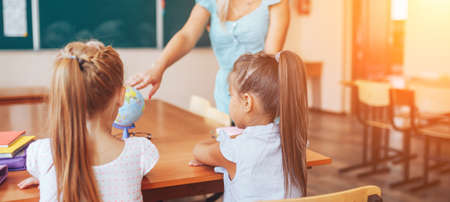 Geography teacher shows two schoolgirls on a globe, individual tuition, elective.の写真素材