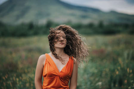 Close-up photo of a girl in an orange dress against a background of mountains, portrait photo of a young girl.の写真素材