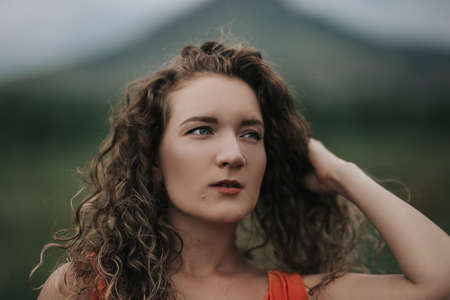 Close-up photo of a girl in an orange dress against a background of mountains, portrait photo of a young girl.の写真素材