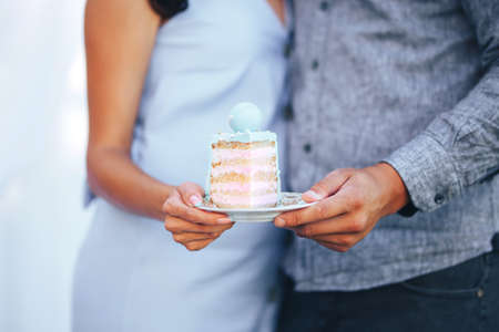 Young couple are hugging and holding a plate with a piece of cakeの写真素材
