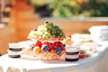 Long table covered with a tablecloth on which there is a lot of food, food in plates.の写真素材