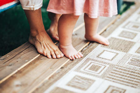 A pair of toddler's feet and a pair of adult feet, the first steps of a child, caring for relatives.の写真素材