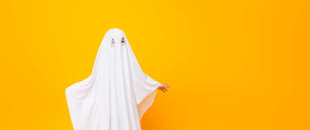 Little kid wearing cute halloween ghost costume on yellow background.の写真素材