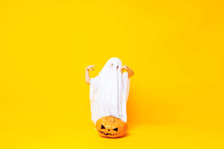 Little kid wearing cute halloween ghost costume on yellow background.の写真素材