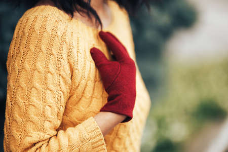 Woman with short hair in a yellow knitted sweater and red gloves.の写真素材