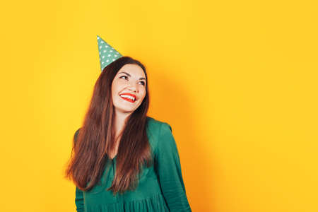 Happy beautiful girl dancing in a green dress on a yellow background, beautiful smile, photo for advertising.の写真素材