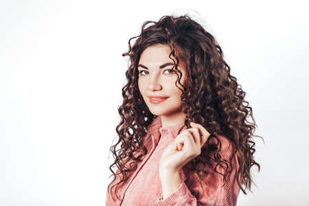Beautiful woman with curly hair posing at camera on white backgroundの写真素材