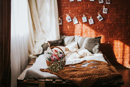A large bed of pallets with pillows, on the bed there is a large basket of flowers of different...