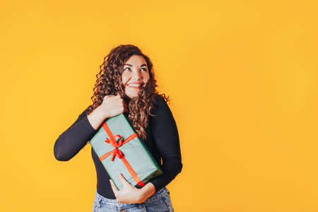 Woman holding large box in her hands. Gift in green packaging with red ribbon and red bow. Gift for woman for holiday or special occasion.の写真素材