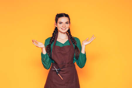 A woman wears a brown apron, a universal service uniform for the population, a uniform for salesmen and a barista, a woman throws her arms up to the sides.の写真素材