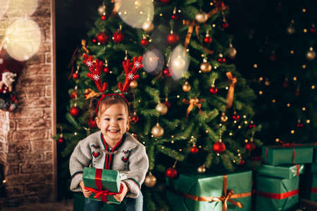 A girl holding a large box in a green package and a bow with a gift. Christmas mood.の写真素材